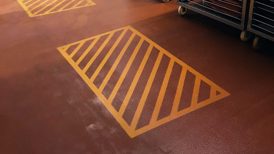 Yellow projected floor marking of a keep clear safety zone in a fish factory.