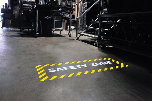 Yellow and white projected floor marking of a safety zone in a warehouse.