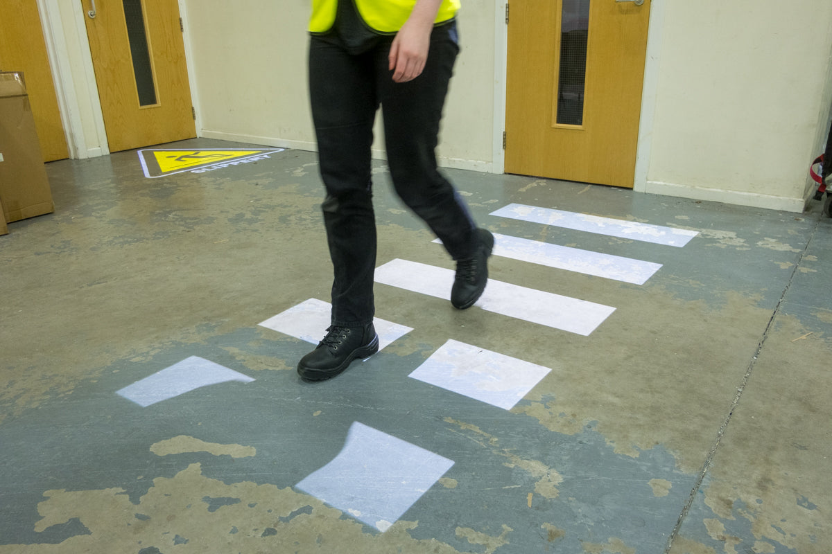 Projected signage of a zebra crossing on warehouse floor.